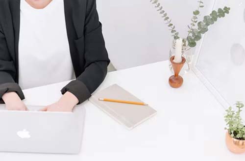 A person in business attire typing on a Macbook. p.jpg
